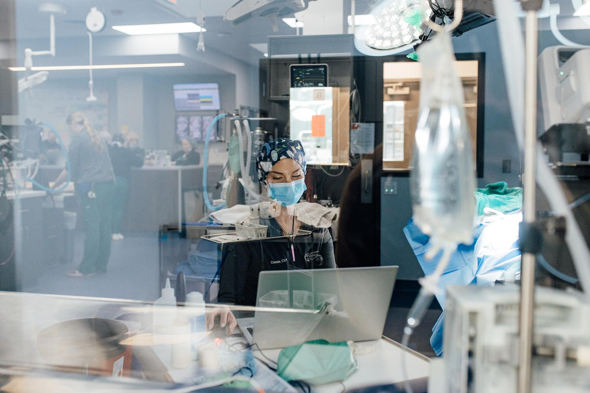 doctor looking at computer with window reflecting surgery suite